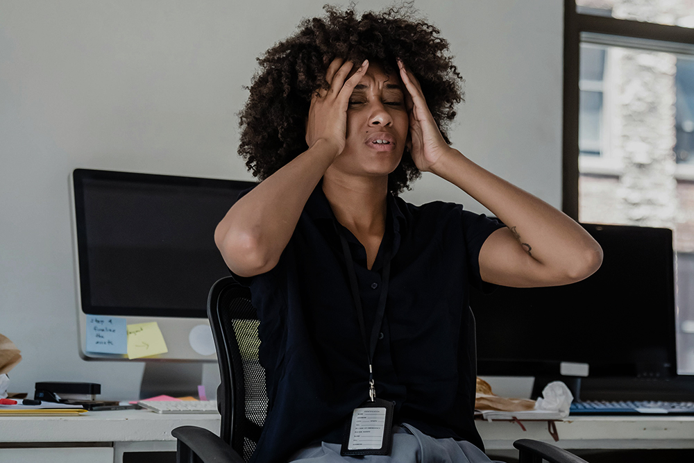 Cat owner stressed at work desk wondering what is happening at home